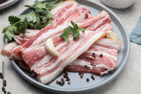 Fototapeta Slices of tasty pork fatback with spices on grey table, closeup