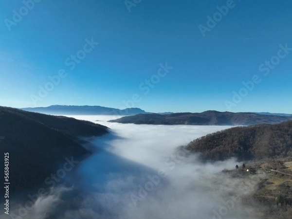 Fototapeta Aerial View. Flying over the high mountains in beautiful clouds. Aerial Drone camera shot. Air pollution clouds over Sarajevo in Bosnia and Herzegovina. 