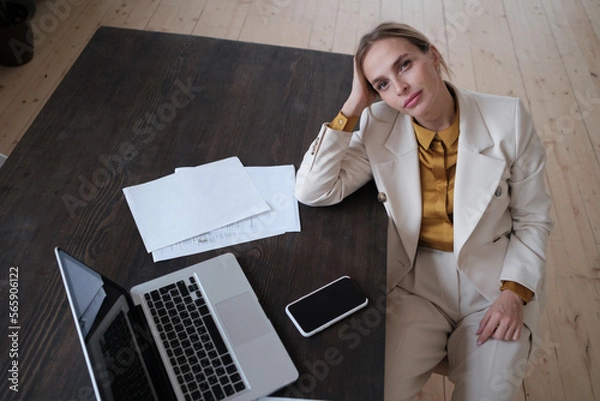 Fototapeta Photo of beauty female worker businesswoman dressed in formal wear looking at camera while working and sitting at desk in office isolated over white background