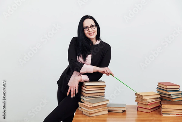 Fototapeta a teacher with a school pointer points to a stack of books to read