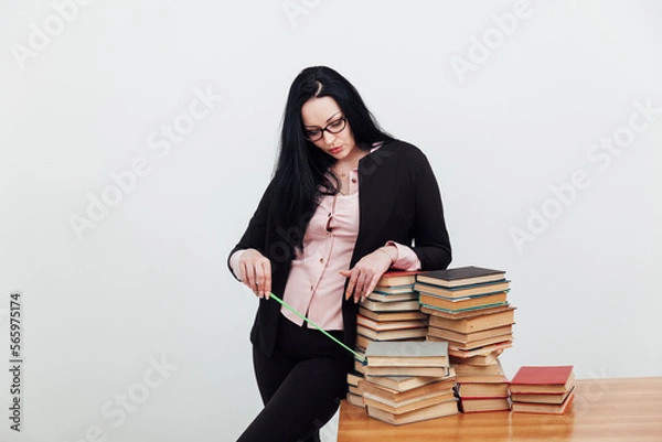 Fototapeta a teacher with a school pointer points to a stack of books to read