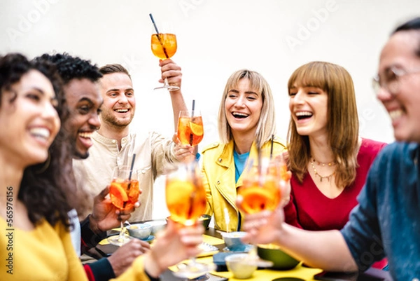 Fototapeta Young millenial people toasting spritz at cocktail bar garden patio - Trendy beverage life style concept with friends having fun together toasting fancy drinks on happy hour time - Bright warm filter