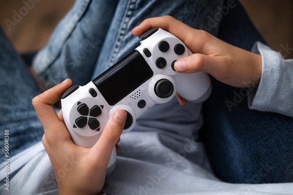 Fototapeta kids hands with joystick, child playing video game console while sitting at home, real people, leisure concept.