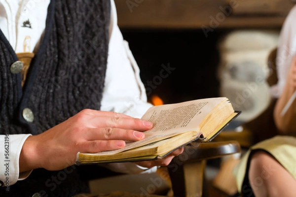 Fototapeta Junger Mann in einer Almhütte liest Bibel