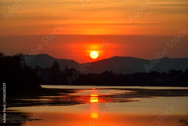 Obraz The sun is setting over the mountain there is a reflection on the water