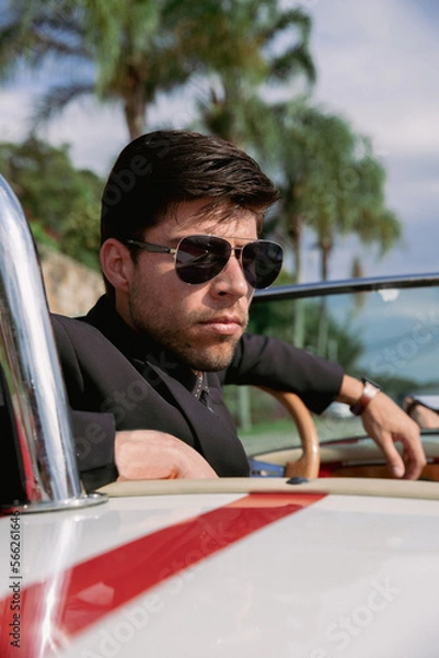 Obraz young man in a convertible car looking out to sea, man in car