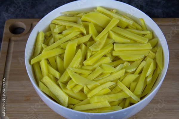 Fototapeta Sliced potatoes for pan frying. Yellow potatoes in a bowl