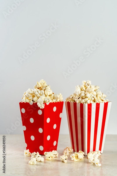 Fototapeta two bags of popcorn in red and white on a light background, front view, copy space
