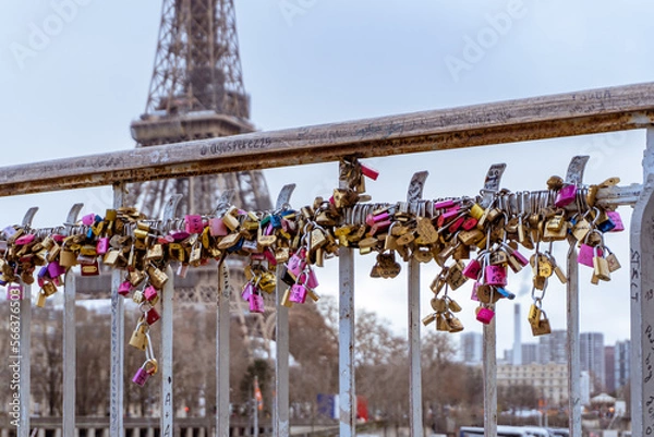 Fototapeta Love locks line the railings of the Debilly Footbridge, a pedestrian bridge crossing the Seine river near the Eiffel Tower.