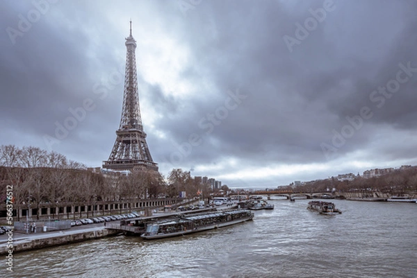Fototapeta A view across the Seine of the Eiffel Tower under dramatic clouds. 