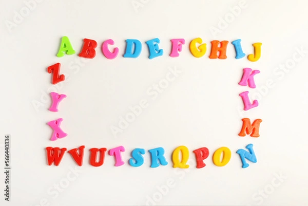 Fototapeta Frame of colorful magnetic letters on white background, flat lay with space for text. Alphabetic order