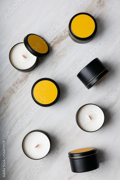 Fototapeta Group of wax candles in a tin box view from above against a background of marble. 