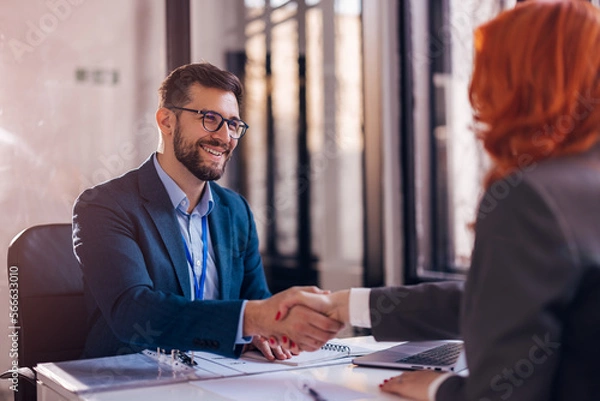 Obraz Happy bank manager shaking hands with a client after successful agreement in the office. 