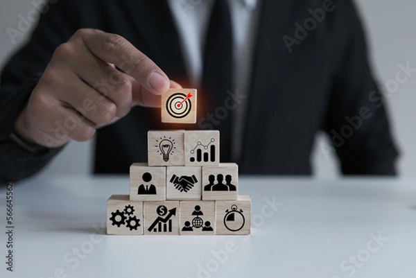 Fototapeta Businessmen pick up wooden cubes with target focus icons, success focus concept by goal setting and strategizing and business cooperation, good tools and communication enable business growth.