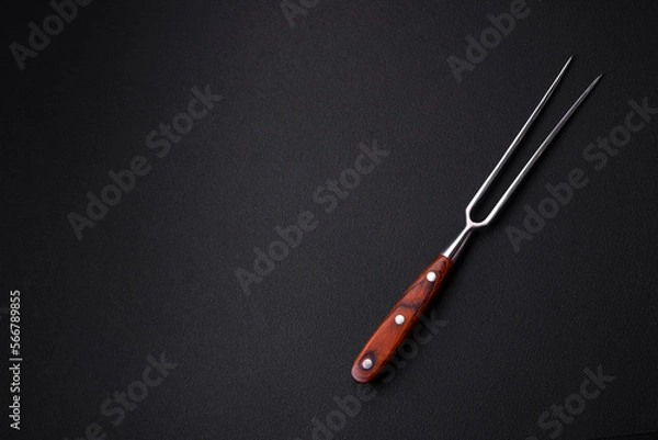 Fototapeta Metal kitchen fork on a dark textured concrete background