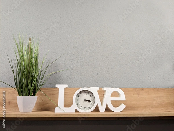 Fototapeta on a wooden shelf there is a green flower in a pot and a clock in the inscription love
