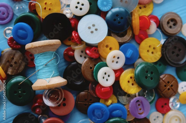 Fototapeta A bunch of colored buttons and a spool of thread and a needle