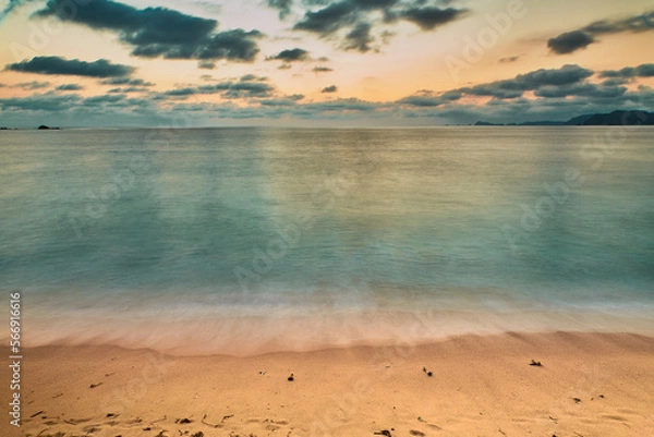 Fototapeta sunset on the beach and the sun is setting on the horizon