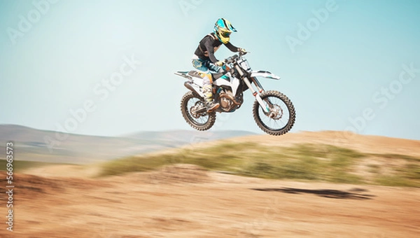 Fototapeta Motorcycle, offroad driving and air jump in desert, blue sky and freedom. Driver, cycling and power stunt on dirt track, competition and motorbike performance on adventure course for fast action show