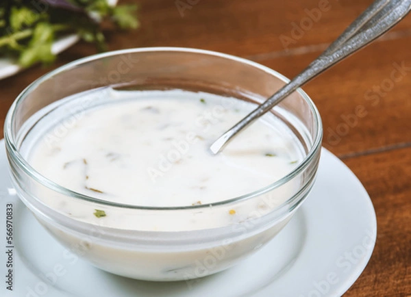 Obraz yogurt soup with herbs in a plate on a wooden table.spas