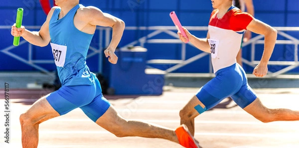 Obraz two male athletes with relay baton in hands run at competition