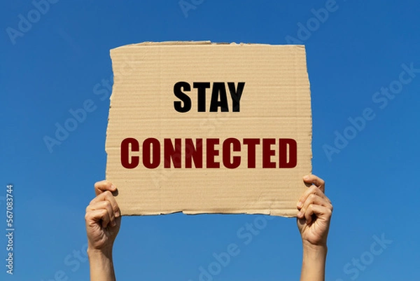 Fototapeta Stay connected message on box paper held by 2 hands with isolated blue sky background. This text can be used for business concept about staying connected with customer or business partner.