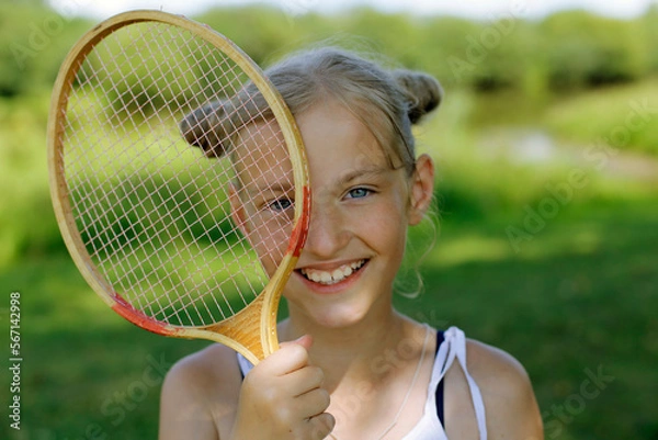 Obraz Blonde girl with a badminton racket on a green background. Active rest in summer.