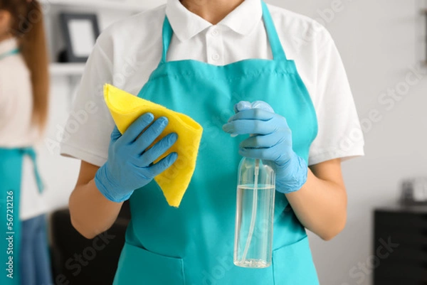 Fototapeta Female janitor with rag and detergent in office, closeup