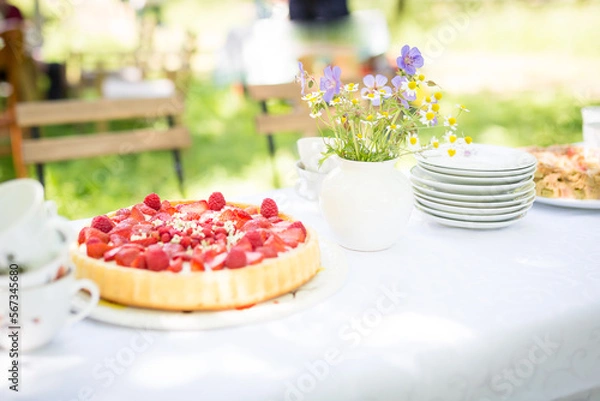 Obraz Familiennachmittag im Grünen mit  weißem Tischtuch , einem Blumensträußchen, Kaffee und Erdbeeertorte.