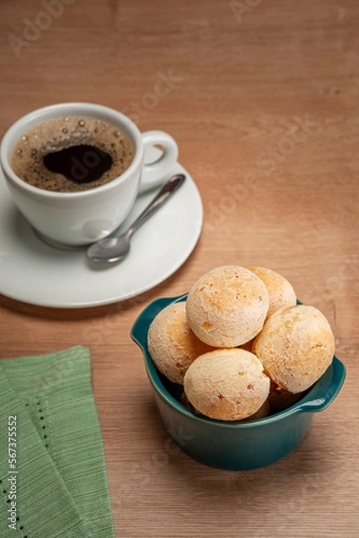 Fototapeta Cheese breads in a green ramekin with a cup of coffee on wooden table.