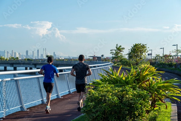 Obraz couple doing sports in cinta costera, with the skyline behind panama city