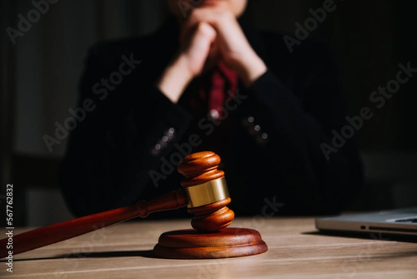 Fototapeta Justice and law concept.Male judge in a courtroom with the gavel, working with, computer and docking keyboard, eyeglasses, on table in morning light