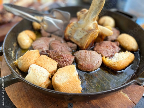 Fototapeta Fillet steak in olive oil served on a skillet with pieces of white bread