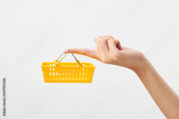 Obraz 노란색 작은 장바구니를 손가락에 걸치고 들고 있는 여자의 손