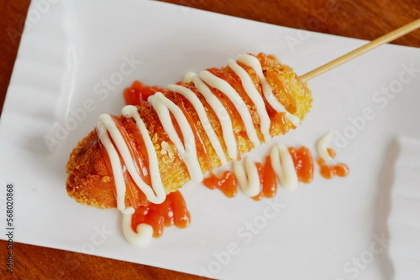 Fototapeta Korean corn dog or Korean hot dog is a popular street food made of sausages or mozzarella cheese on sticks and wrapped with yeasted batter and coated with breadcrumbs then deep fried to golden.