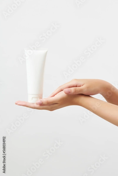 Obraz 흰색 튜브형 화장품 목각 제품을 손바닥에 올려 들고 있는 아름다운 여성의 손