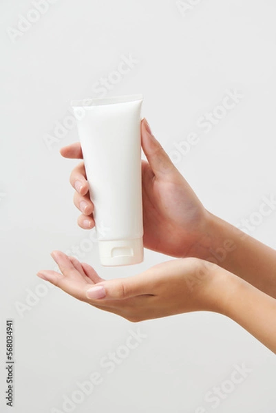Obraz 흰색 목각 모형 튜브형 화장품을 들고 있는 여성 모델의 아름다운 손