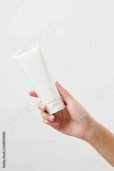 Obraz 흰색 튜브 형태의 화장품 목각 모형을 들고 있는 20대 여성의 손