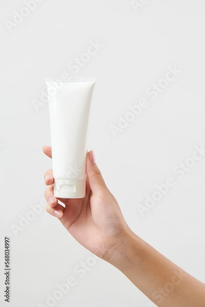 Obraz 흰색 튜브 형태의 화장품 목각을 들고 있는 여성의 손