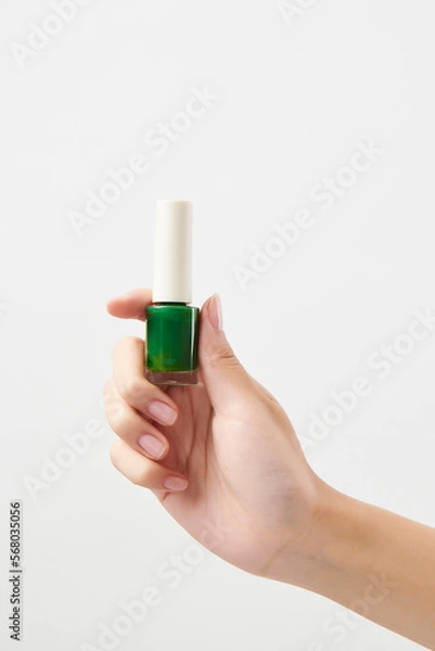 Obraz 녹색 메니큐어를 들고 있는 여성의 손