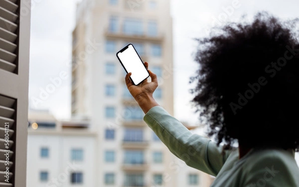 Obraz Afro American woman using a smartphone with a white screen for mock up design. Business woman taking a selfie with mock-up screen