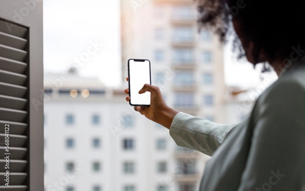 Obraz Afro american woman using a smartphone with white screen for mock up design.