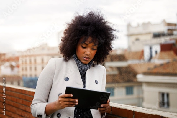 Obraz Afro American business woman using a tablet on the roof of a building. Entrepreneur using a tablet