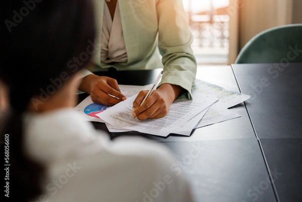 Obraz Business coworkers with documents at the office. Afro-American woman signing a document at the office 