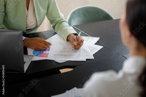Obraz Business coworkers with documents at the office. Afro-American woman signing a document at the office 