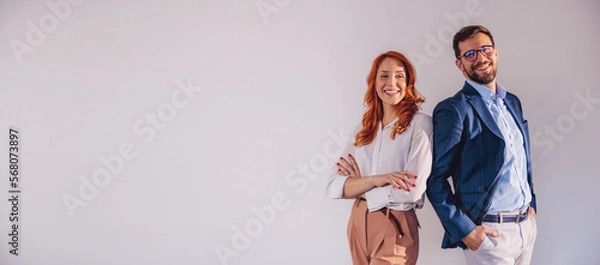 Obraz Business partners posing in front of gray background, looking at camera and smiling.