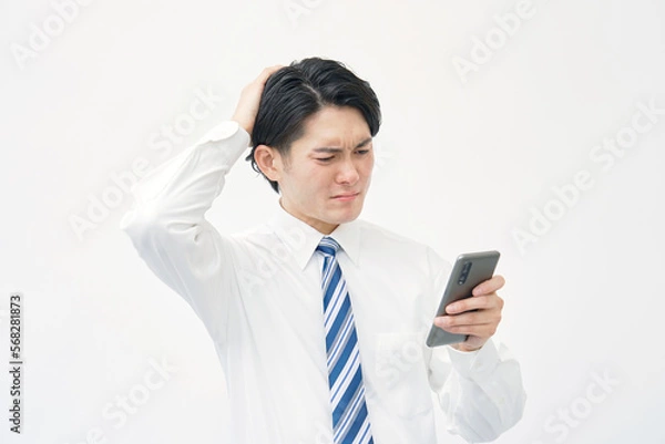 Fototapeta スマホを持って悩むビジネスマン　白背景