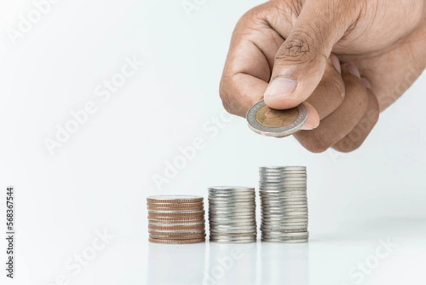 Fototapeta hand putting a coin on stacks of coin, money saving concept, financial and business growth concept, white background, copy space.
