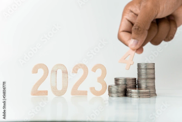 Fototapeta hand putting a coin on stacks of coin, money saving concept, financial and business growth concept, white background, copy space.