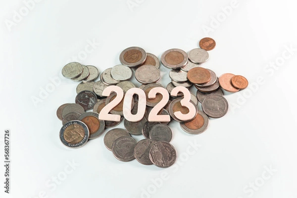 Fototapeta Wooden text of 2023 on pile of money, money saving concept, financial and business growth, white background